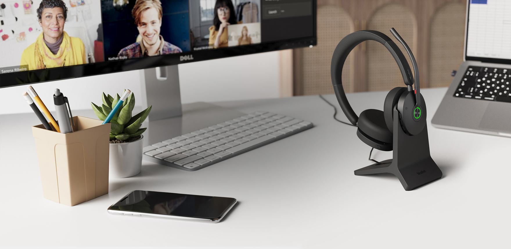 Yealink BH74 Bluetooth headset on its charging stand beside a laptop